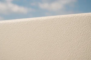 Close-up of a textured beige surface against a blue sky.